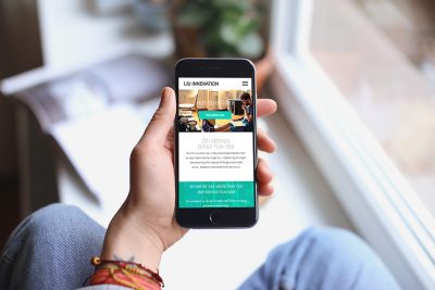 LiU Innovations hemsida på en mobiltelefon. En kvinna håller telefonen i handen. Bakgrunden är suddig.