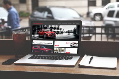 Zetterblom bils hemsida på en laptop i en cafémiljö. Datorn är i fokus, bakgrunden är suddig. På sidan av laptopen ligger ett anteckningsblock.